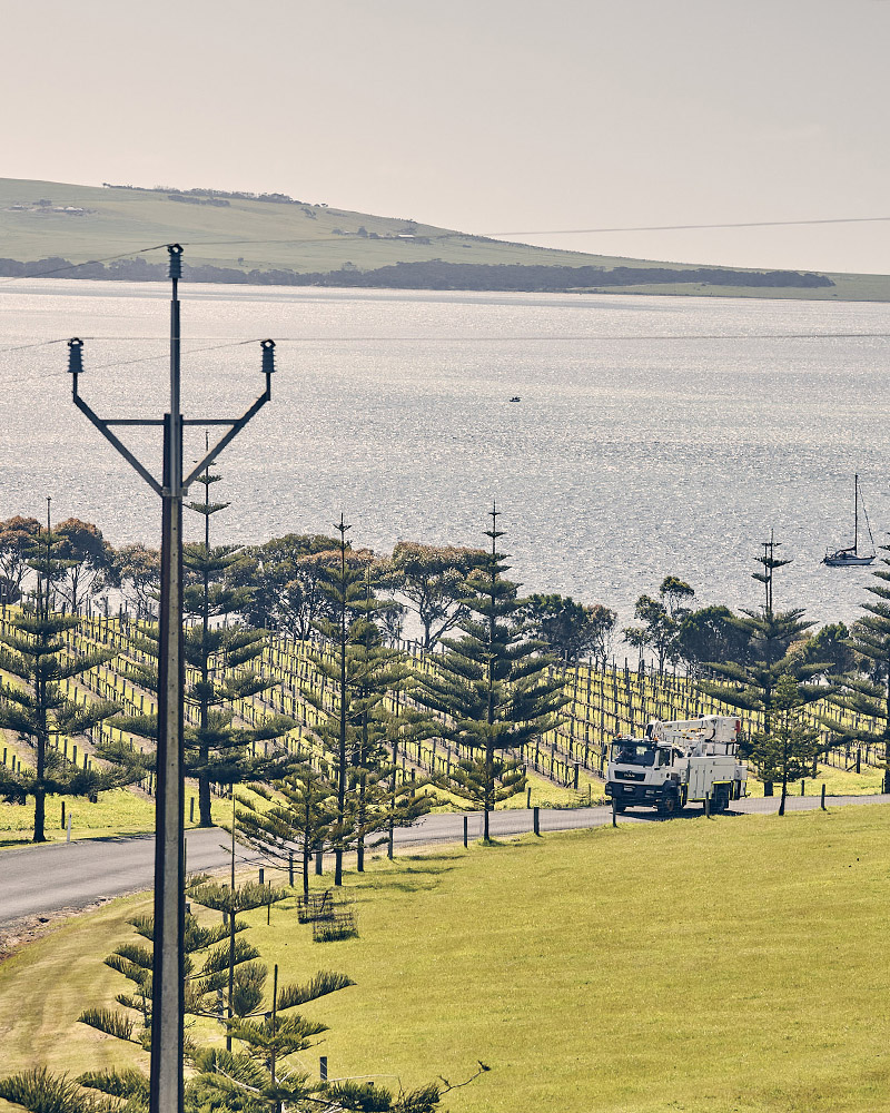 An SA Power Networks elevated work platform (EWP) truck drives on a scenic coastal route on Kangaroo Island.
