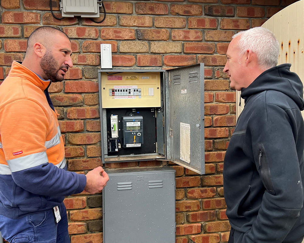 Flexible Exports customer Darren with SA Power Networks Energy Advisory Harry speak in front of an electricity meter box