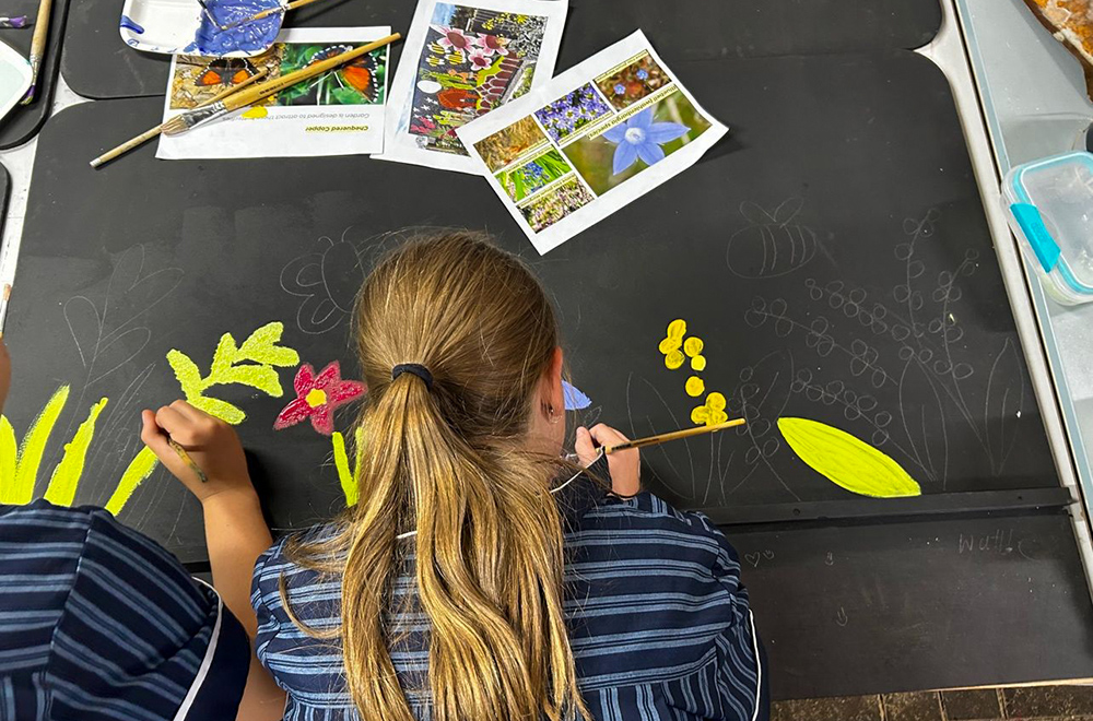 Students work on an artwork that will eventually be displayed in the butterfly garden.